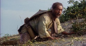 Movie still from “Kagemusha” (1980), directed by Akira Kurosawa – An old man sitting on the ground with his head on his back; Medium shot, Low angle