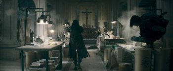 Movie still from “Keanu” (2016), directed by Peter Atencio – A person standing in front of a cross in a room; Wide shot, Low angle