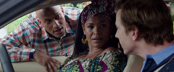 Movie still from “Keanu” (2016), directed by Peter Atencio – A woman in a colorful dress in a car with two other people; Close Up shot, Over the shoulder angle