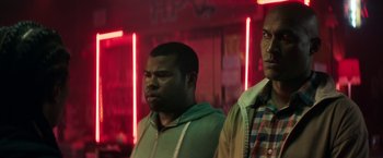 Movie still from “Keanu” (2016), directed by Peter Atencio – Two men standing next to each other in front of neon lights; Medium shot, Over the shoulder angle