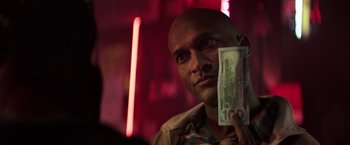 Movie still from “Keanu” (2016), directed by Peter Atencio – A man holding a $ 1 0 0 bill up to his face; Close Up shot, Over the shoulder angle