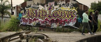 A wall covered in graffiti next to an abandoned car