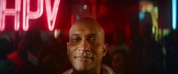 Movie still from “Keanu” (2016), directed by Peter Atencio – A person smiling with a red light in the background; Close Up shot, Low angle