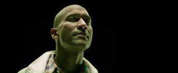 Movie still from “Keanu” (2016), directed by Peter Atencio – A man with a bald head looking upward; Close Up shot, Low angle