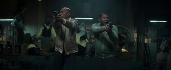 Movie still from “Keanu” (2016), directed by Peter Atencio – A couple of men standing next to each other holding game controllers; Medium shot, Low angle