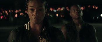 Movie still from “Keanu” (2016), directed by Peter Atencio – A person wearing a jacket with lights in the background; Close Up shot, Over the shoulder angle