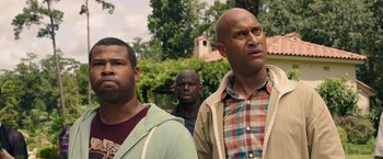 Movie still from “Keanu” (2016), directed by Peter Atencio – A group of men standing next to each other in front of trees; Close Up shot, Over the shoulder angle