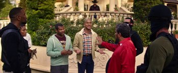 Movie still from “Keanu” (2016), directed by Peter Atencio – A group of men standing next to each other on a porch; Medium shot, Over the shoulder angle