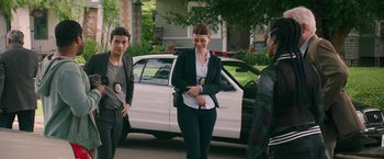 A group of people standing next to each other near a white car