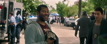 Movie still from “Keanu” (2016), directed by Peter Atencio – A man standing on a sidewalk with a cat in his hand; Medium shot, Over the shoulder angle