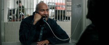 Movie still from “Keanu” (2016), directed by Peter Atencio – A man sitting at a table talking on a phone; Medium shot, High angle