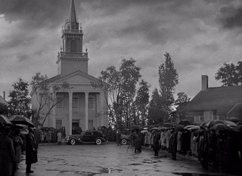 Movie still from “Keeper of the Flame” (1942), directed by George Cukor – An old photo of people gathered in front of a church; Extreme Wide shot, High angle