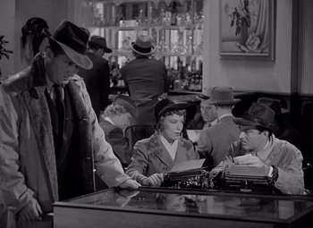 Movie still from “Keeper of the Flame” (1942), directed by George Cukor – A group of people sitting at a table with a typewriter; Medium shot, High angle