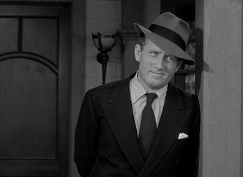 Movie still from “Keeper of the Flame” (1942), directed by George Cukor – A black and white photo of a man wearing a suit and hat; Close Up shot, Low angle