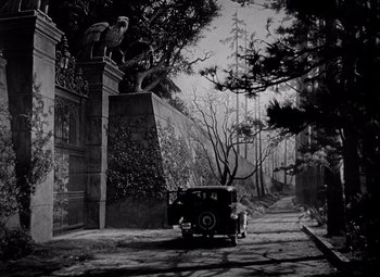 Movie still from “Keeper of the Flame” (1942), directed by George Cukor – An old car parked in front of a wall; Extreme Wide shot, Low angle