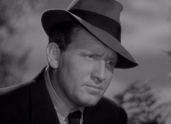 Movie still from “Keeper of the Flame” (1942), directed by George Cukor – A man wearing a suit and a hat; Close Up shot, Low angle