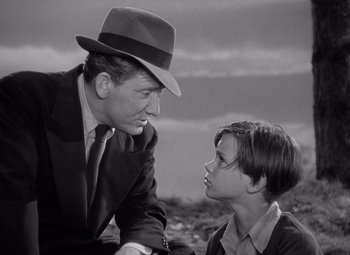Movie still from “Keeper of the Flame” (1942), directed by George Cukor – An older man and a young boy talking to each other; Medium shot, High angle