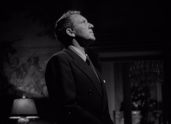 Movie still from “Keeper of the Flame” (1942), directed by George Cukor – A man in a suit and tie looking up; Medium shot, Low angle