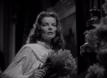 Movie still from “Keeper of the Flame” (1942), directed by George Cukor – A black - and - white photo of a woman holding flowers; Close Up shot, Low angle