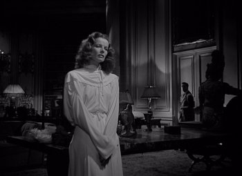 Movie still from “Keeper of the Flame” (1942), directed by George Cukor – A black and white photo of a woman in a white dress; Medium shot, Low angle