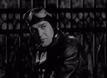Movie still from “Keeper of the Flame” (1942), directed by George Cukor – A black and white photo of a man wearing a helmet; Close Up shot, Low angle