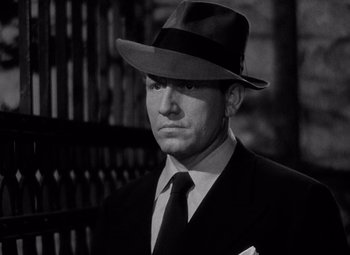 Movie still from “Keeper of the Flame” (1942), directed by George Cukor – A black and white photo of a man in a suit and hat; Close Up shot, Low angle