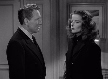 Movie still from “Keeper of the Flame” (1942), directed by George Cukor – A man and a woman standing next to each other in a room; Medium shot, Over the shoulder angle