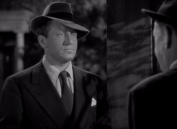 Movie still from “Keeper of the Flame” (1942), directed by George Cukor – A black and white photo of a man in a suit and hat; Close Up shot, Over the shoulder angle