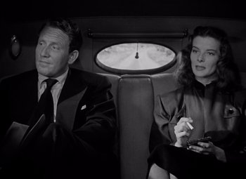 Movie still from “Keeper of the Flame” (1942), directed by George Cukor – A man and a woman sitting in the back of a car; Medium shot, High angle