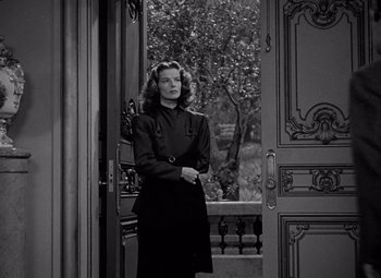 Movie still from “Keeper of the Flame” (1942), directed by George Cukor – A woman standing in front of an open door; Medium shot, High angle