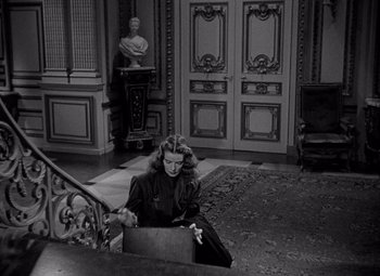 Movie still from “Keeper of the Flame” (1942), directed by George Cukor – A woman sitting on the ground in a room; Medium shot, High angle