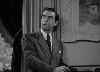 Movie still from “Keeper of the Flame” (1942), directed by George Cukor – Black and white photograph of a man wearing a suit and tie; Medium shot, High angle