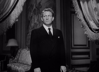 Movie still from “Keeper of the Flame” (1942), directed by George Cukor – A black and white photo of a man in a suit and tie; Medium shot, Low angle