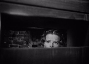 Movie still from “Keeper of the Flame” (1942), directed by George Cukor – A black and white photo of a woman peeking through a window; Close Up shot, High angle