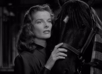 Movie still from “Keeper of the Flame” (1942), directed by George Cukor – A black and white photo of a woman and a horse; Close Up shot, Low angle