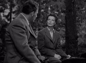 Movie still from “Keeper of the Flame” (1942), directed by George Cukor – A man and a woman sitting on a bench in the woods; Medium shot, High angle