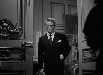 Movie still from “Keeper of the Flame” (1942), directed by George Cukor – A black and white photo of a man in a suit and tie; Medium shot, Low angle