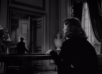 Movie still from “Keeper of the Flame” (1942), directed by George Cukor – A woman sitting at a table in front of a man; Medium shot, Over the shoulder angle