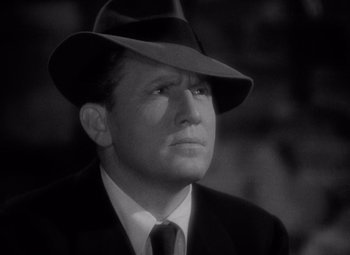 Movie still from “Keeper of the Flame” (1942), directed by George Cukor – A man wearing a suit and a hat looking to his left; Close Up shot, Low angle