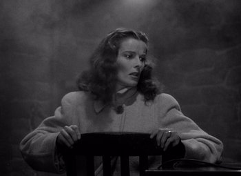 Movie still from “Keeper of the Flame” (1942), directed by George Cukor – A black and white photo of a woman sitting in a chair; Medium shot, Low angle