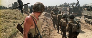 Movie still from “Kelly's Heroes” (1970), directed by Brian G. Hutton – A group of soldiers walking down a dirt road; Wide shot, Over the shoulder angle