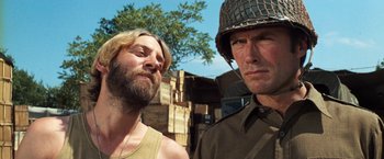 Movie still from “Kelly's Heroes” (1970), directed by Brian G. Hutton – Two men standing next to each other in front of a tree; Close Up shot, Over the shoulder angle