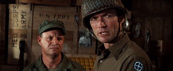 Movie still from “Kelly's Heroes” (1970), directed by Brian G. Hutton – A man in a military uniform standing next to another man in an army uniform; Close Up shot, Over the shoulder angle