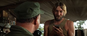 Movie still from “Kelly's Heroes” (1970), directed by Brian G. Hutton – A man looking at his cell phone in front of a mirror; Close Up shot, Over the shoulder angle