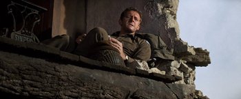 Movie still from “Kelly's Heroes” (1970), directed by Brian G. Hutton – A man sitting on the side of a building; Medium shot, Low angle