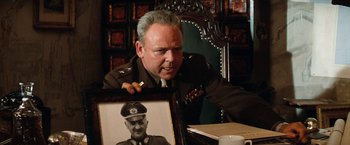 Movie still from “Kelly's Heroes” (1970), directed by Brian G. Hutton – An older man holding a picture of a man in military uniform; Medium shot, Over the shoulder angle