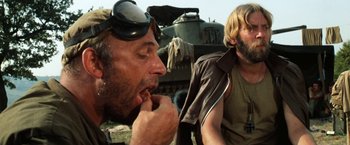 Movie still from “Kelly's Heroes” (1970), directed by Brian G. Hutton – Two men sitting next to each other in front of a tank; Close Up shot, Low angle