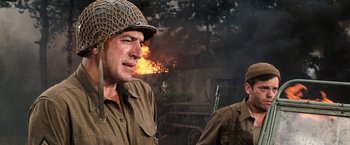 Movie still from “Kelly's Heroes” (1970), directed by Brian G. Hutton – Two men in military uniforms are standing in front of a fire; Close Up shot, Low angle