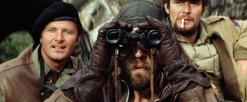 Movie still from “Kelly's Heroes” (1970), directed by Brian G. Hutton – A man in a brown leather jacket looking through a pair of binoculars; Close Up shot, Over the shoulder angle