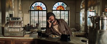 Movie still from “Kelly's Heroes” (1970), directed by Brian G. Hutton – A man sitting at a table talking on a phone; Medium shot, Low angle
